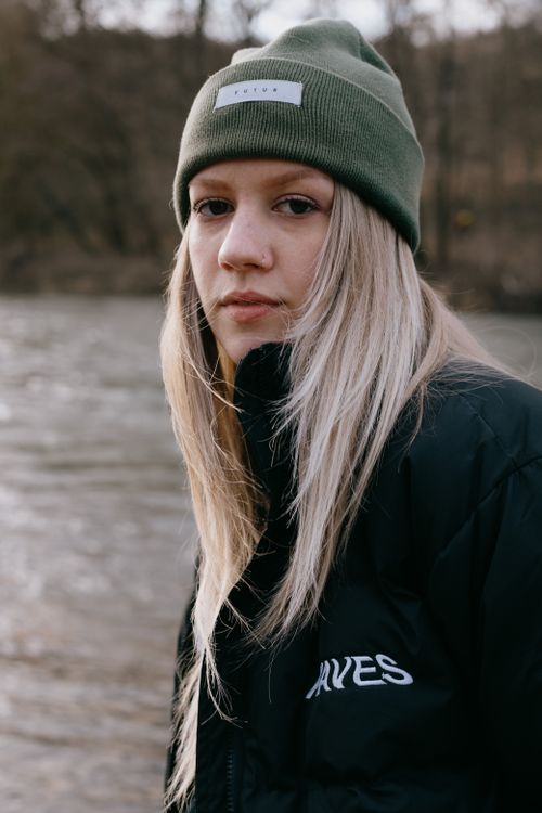 Free A portrait of a woman in a winter jacket and beanie by the river in Durbuy, Belgium. Stock Photo