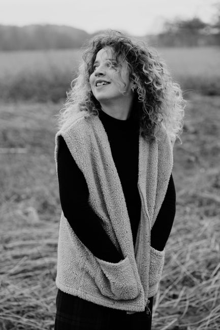 Striking black and white portrait of a woman standing in the grasslands of Durbuy, Belgium.