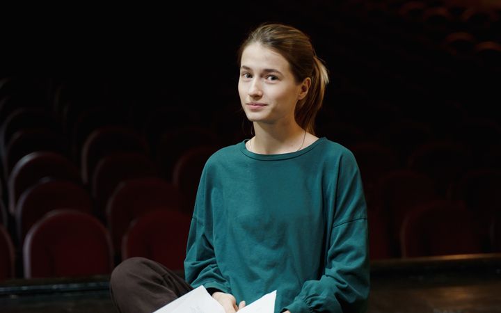 Young actress rehearsing her lines on an empty theater stage. Preparing for a dramatic performance.