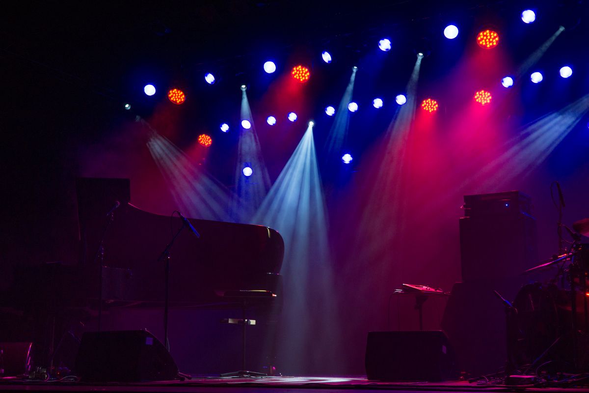 Grand piano under spotlights on a dark concert stage