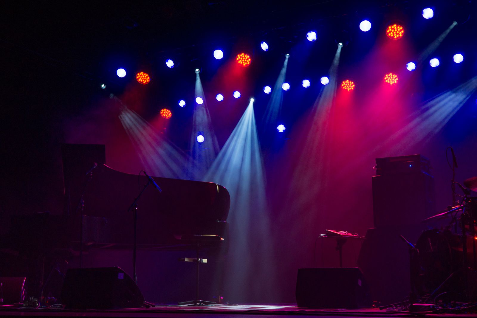 Grand piano under spotlights on a dark concert stage