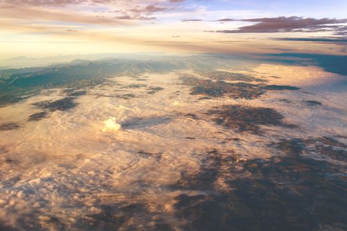 Free Breathtaking aerial view of a mountainous landscape covered with clouds at dawn, showcasing magical light. Stock Photo