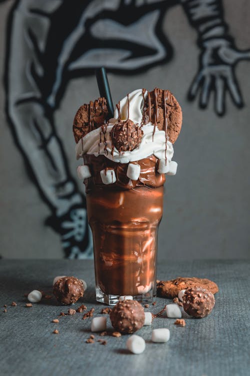Glass with chocolate milkshake with cookies and marshmallows with cream