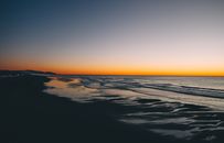 Bright sundown over ocean and sandy shore