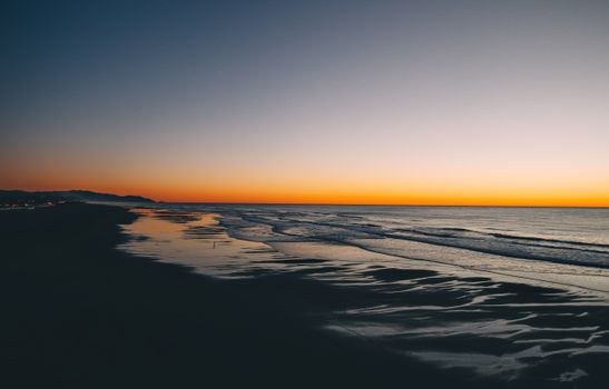 Bright sundown over ocean and sandy shore