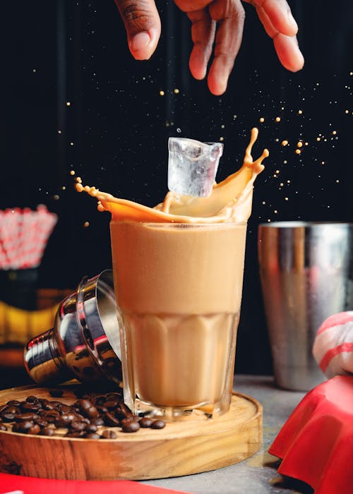 A Photo of Hand Putting Ice on a Coffee