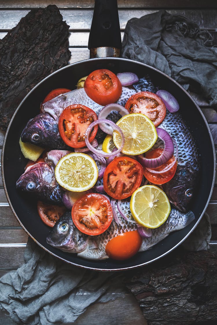 Uncooked Fish With Sliced Lemons And Tomatoes