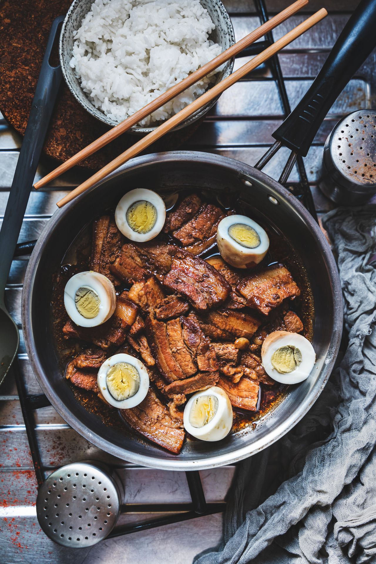 Filipino adobo with meat, hard-boiled eggs and rice in a dark glossy soy-vinegar sauce