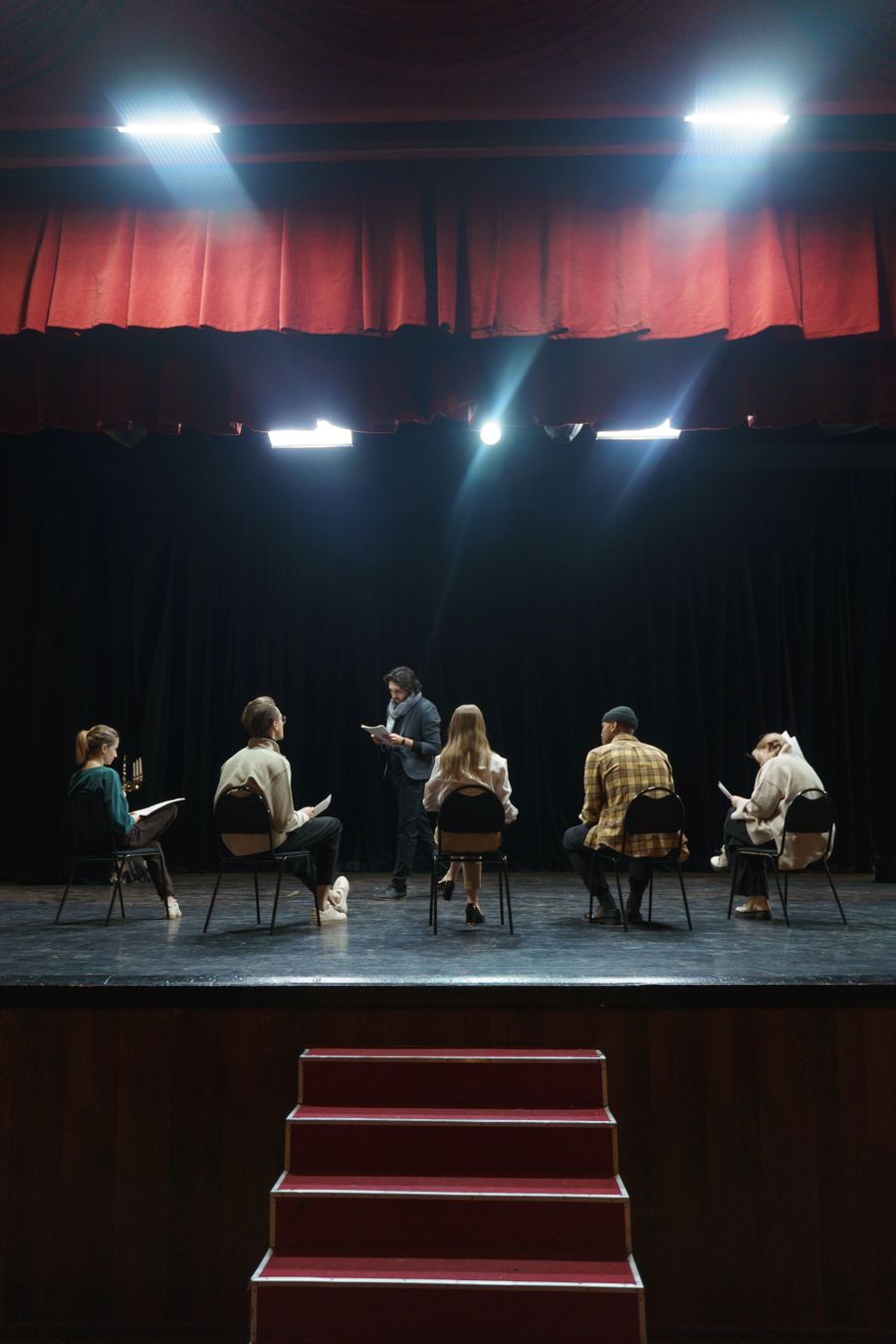 Grupo de atores em ensaio sob luz de palco