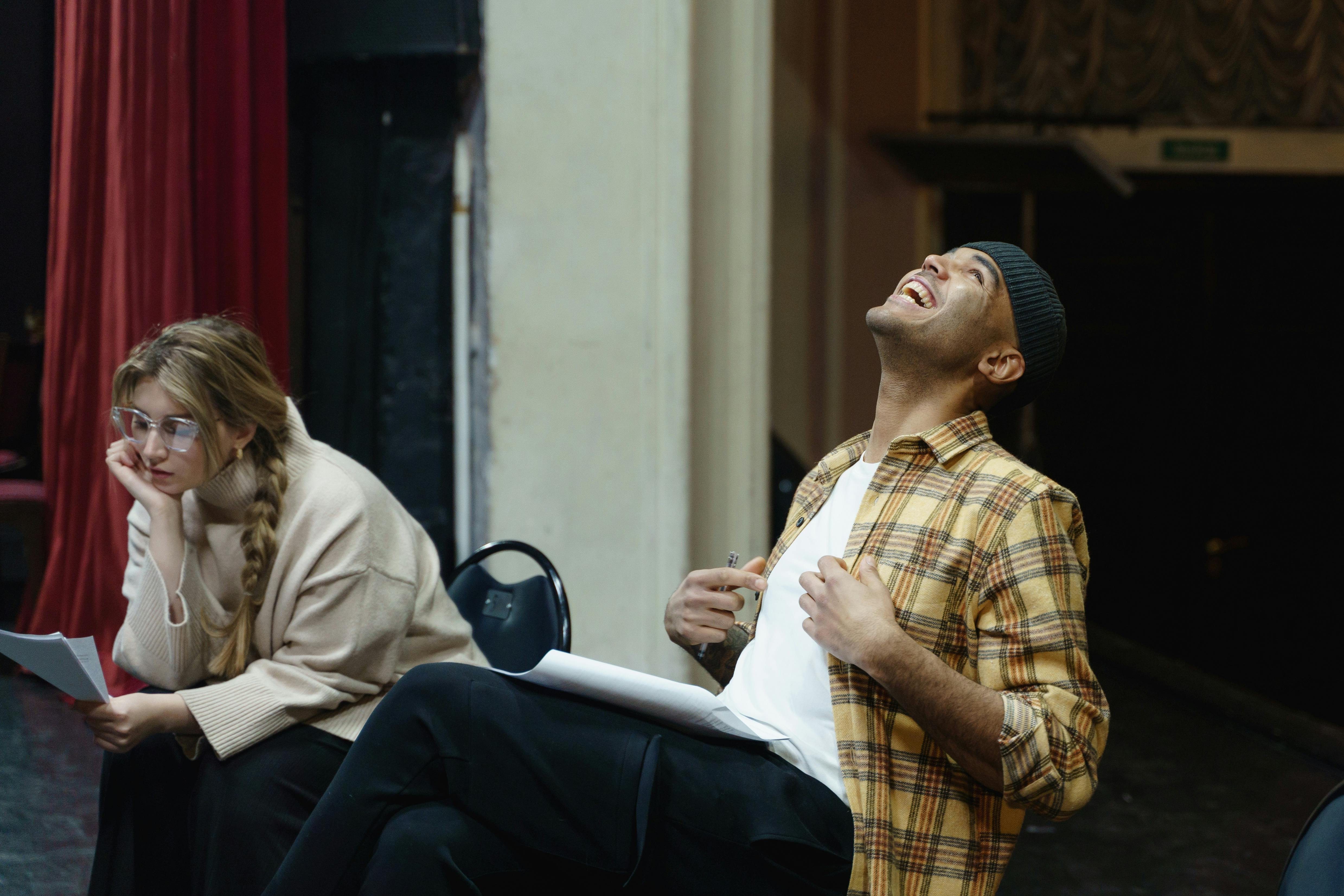 man laughing beside a woman studying