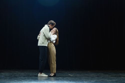 Free A couple intimately embracing on stage in dramatic lighting. Stock Photo