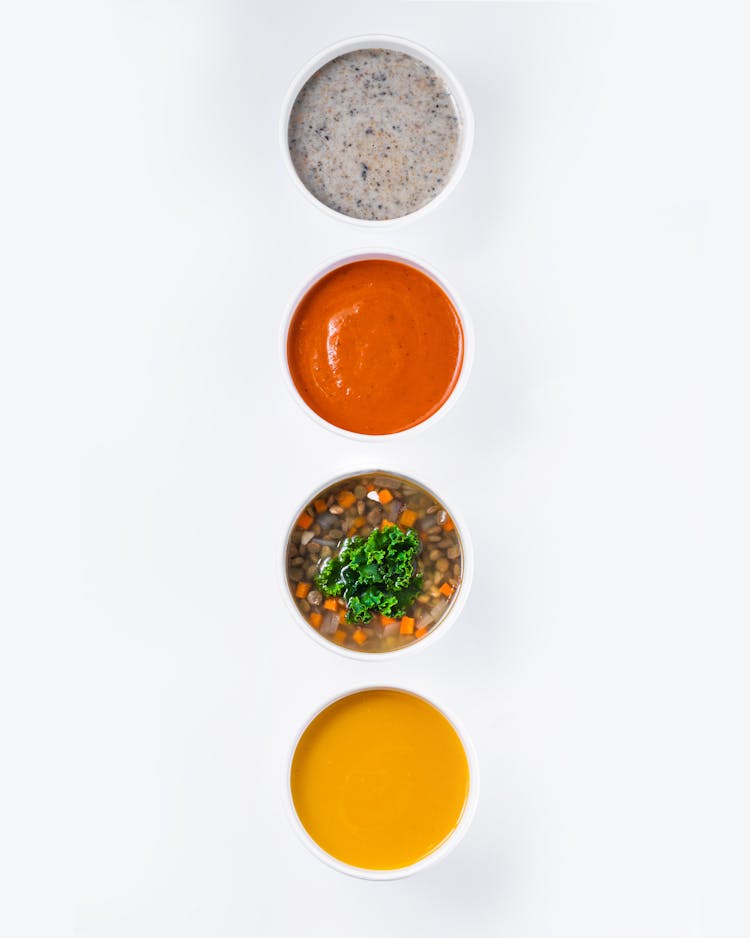 A Bowl Of Soup With Assorted Dips And Sauces