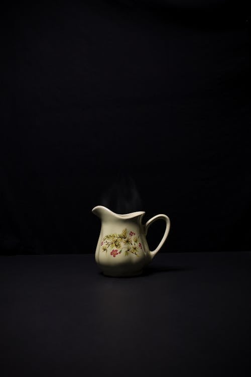 A White Floral Ceramic Teapot on Black Table