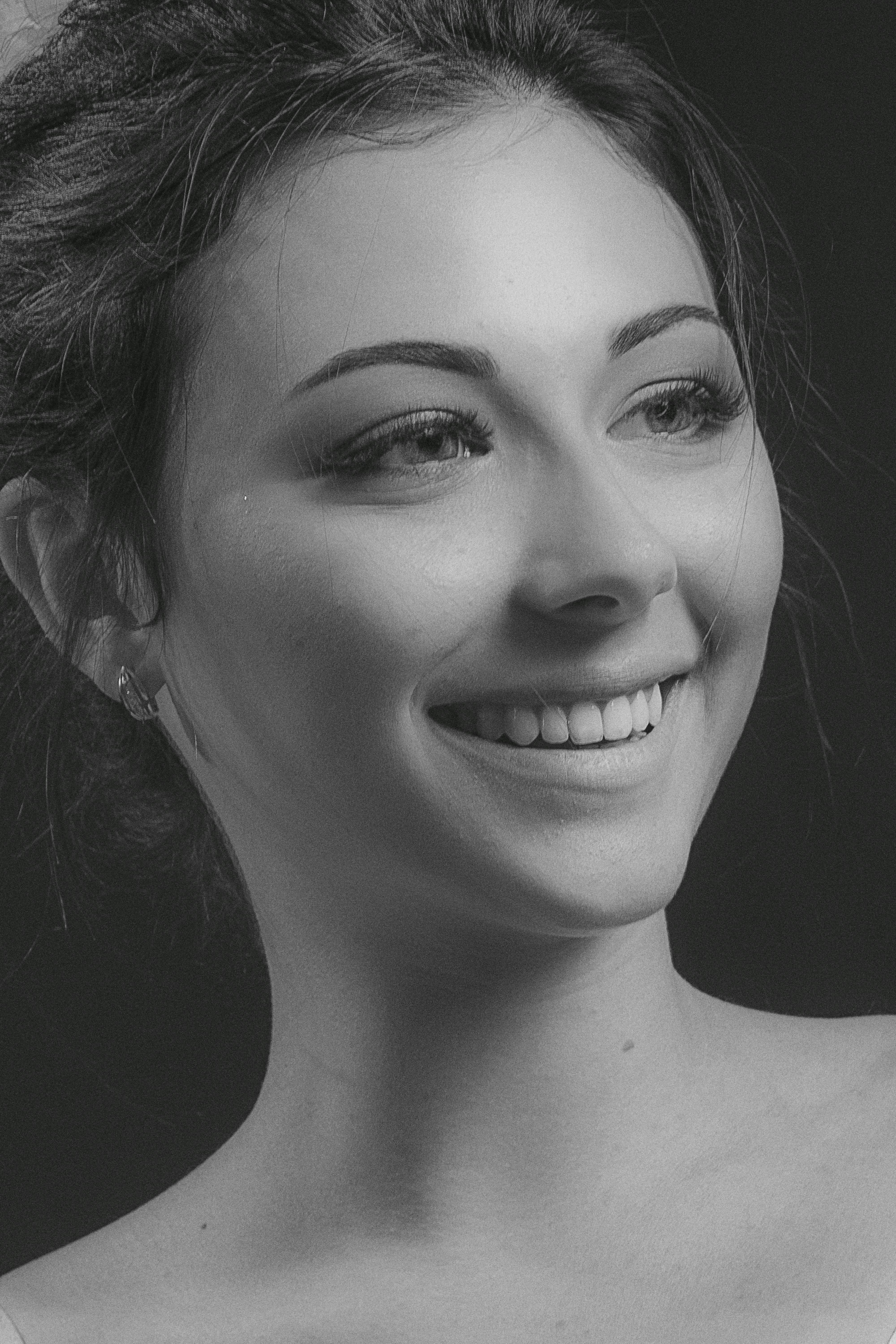 Black and white portrait of a smiling young woman with messy hair.