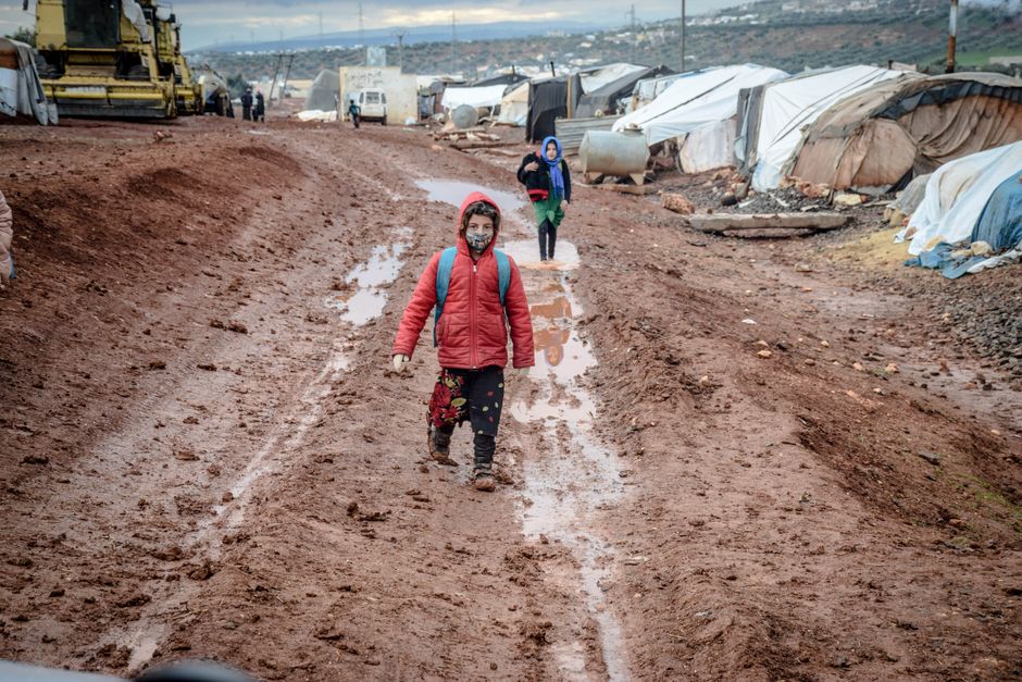 Crianças em campo de refugiados em Idlib, Síria, representando o impacto humano das crises globais.