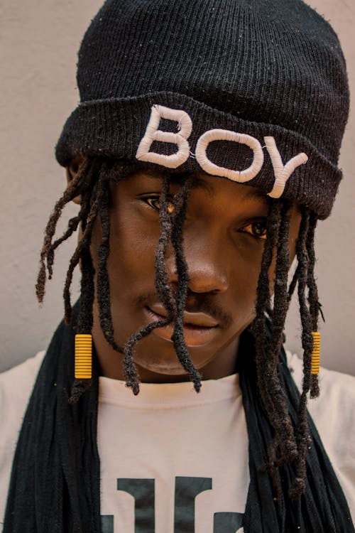 Serious African American male with dreadlocks near wall