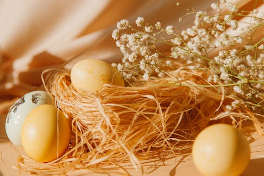 A close-up of colorful Easter eggs in a straw nest with delicate white flowers.