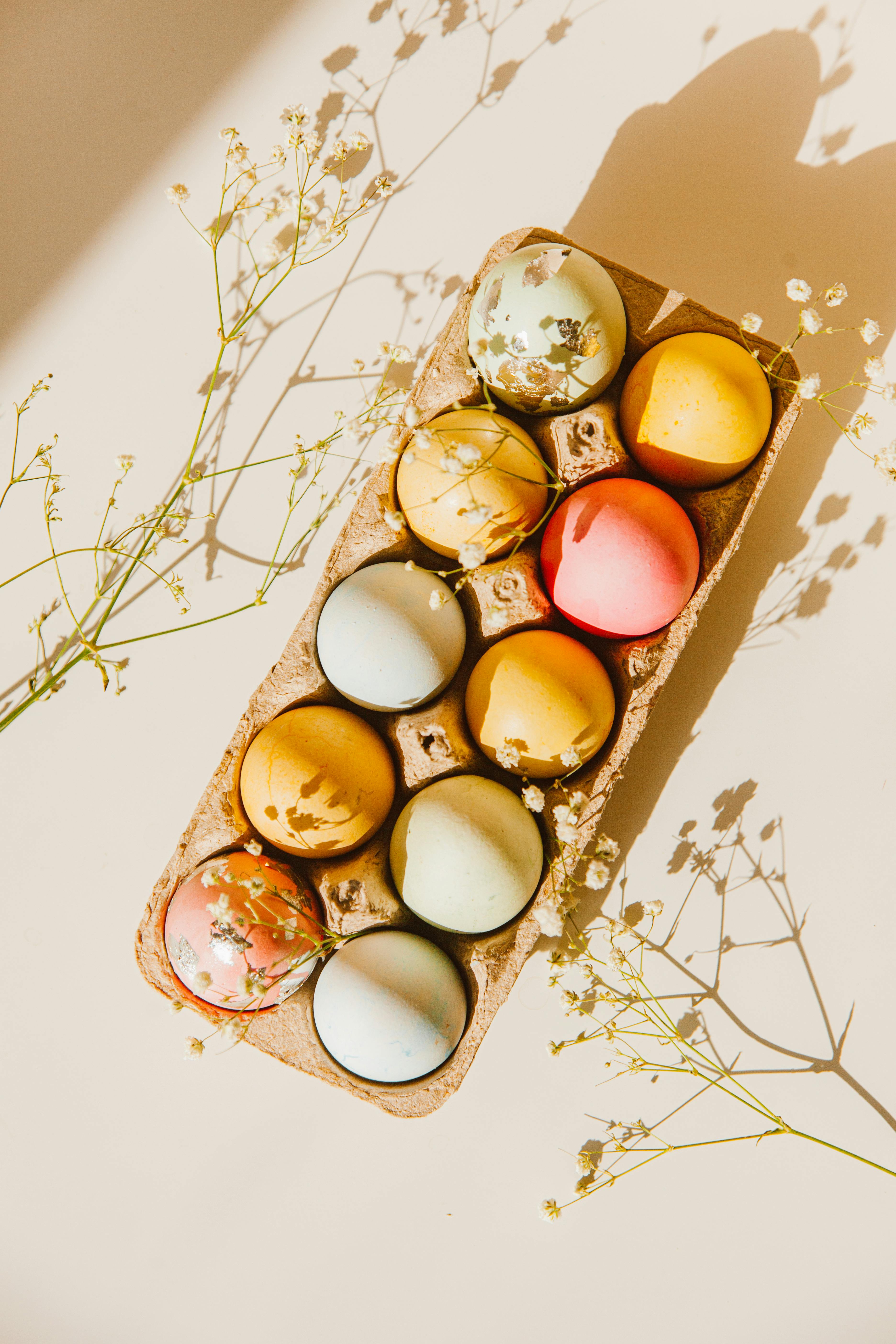 Brightly colored Easter eggs in a carton with floral decoration, perfect for spring celebrations.