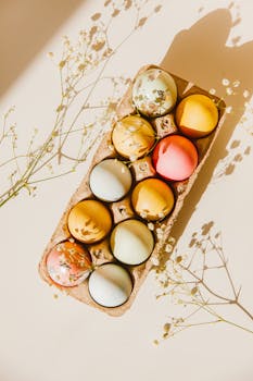 Brightly colored Easter eggs in a carton with floral decoration, perfect for spring celebrations.