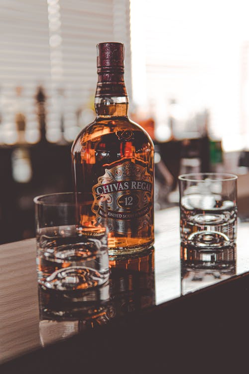 Brown Glass Bottle Beside Clear Drinking Glass