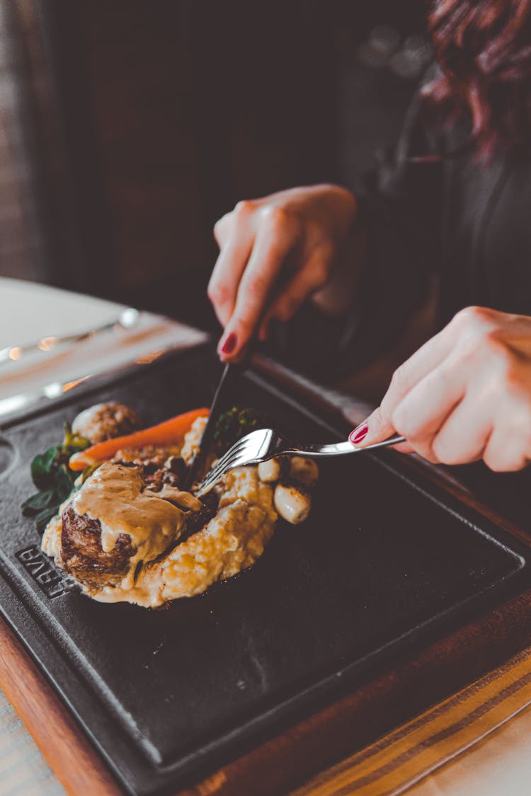 Person Holding Stainless Steel Fork And Knife While Eating 