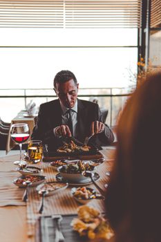 A man in a suit dining at a restaurant with wine, showcasing a formal and refined atmosphere.