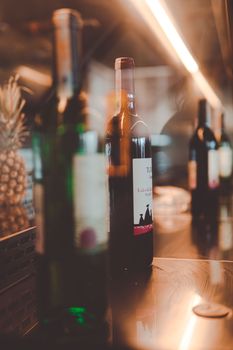 Aesthetic wine bottles on a reflective surface with warm, artistic lighting and a hint of pineapple decor.