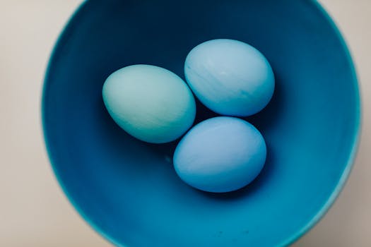 Three pastel blue Easter eggs in a vibrant blue bowl, perfect for holiday decor inspiration.