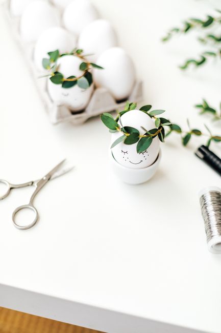 Easter eggs decorated with leafy crowns on a white surface, showcasing creative DIY ideas.