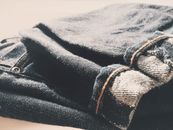 Folded Blue Denim Bottoms on Brown Surface