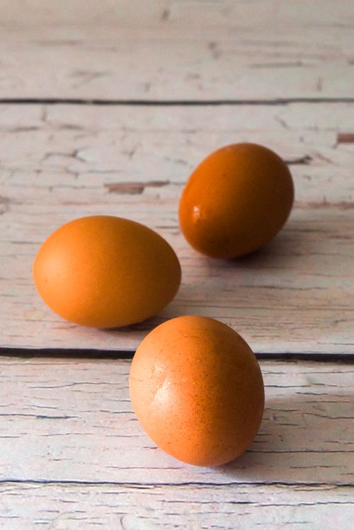 Free Close-up of three brown eggs on a rustic wooden surface, warm and inviting. Stock Photo