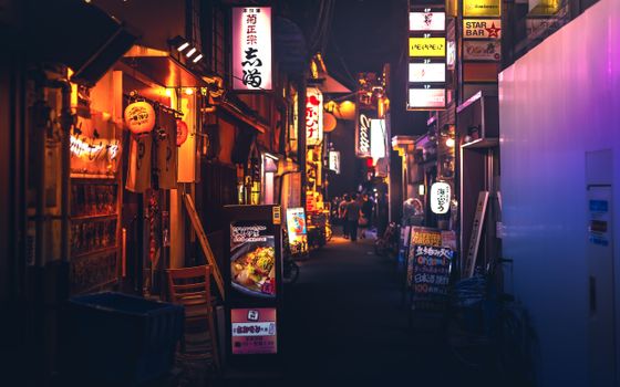 Bustling Japanese night market street with neon lights and people walking through.