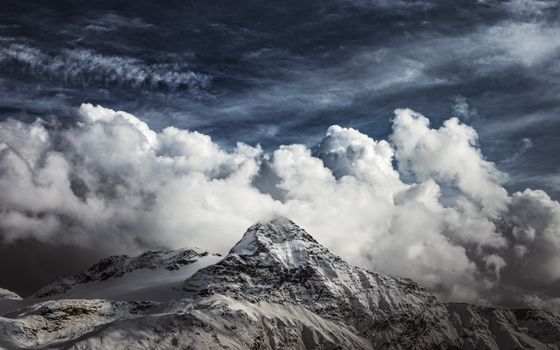 Stunning view of snow-covered peaks under dramatic clouds in Lanzada, Italy.