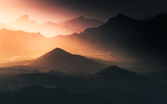 A stunning sunset over the mountains of Santa Cruz de Tenerife, Spain, with dramatic lighting and silhouettes.