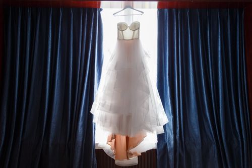 Free A beautiful wedding dress elegantly displayed by a window, ideal for bridal themes. Stock Photo