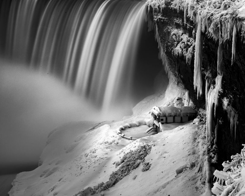 A dramatic black and white capture of the frozen Niagara Falls showcasing its majestic, icy beauty.