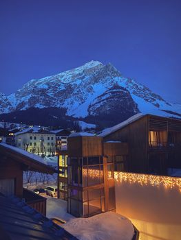 Beautiful evening view of snow-capped mountains and cozy village lights in San Vito di Cadore, Italy.