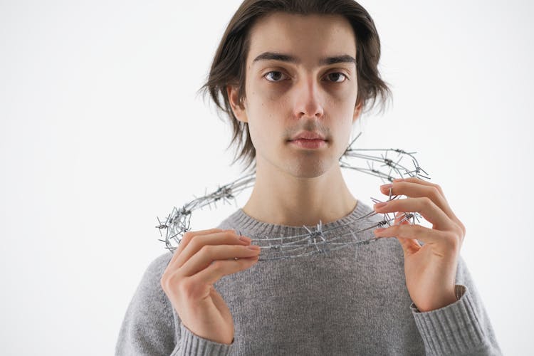 Man In Gray Knit Sweater Holding A Barbed Wire Around His Neck 