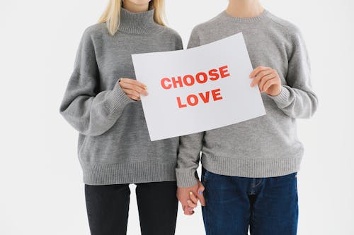 A Couple in Gray Sweater Holding White Paper with Choose Love Print