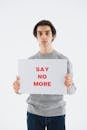 A Young Man Holding a Say No More Print Out on a White Paper