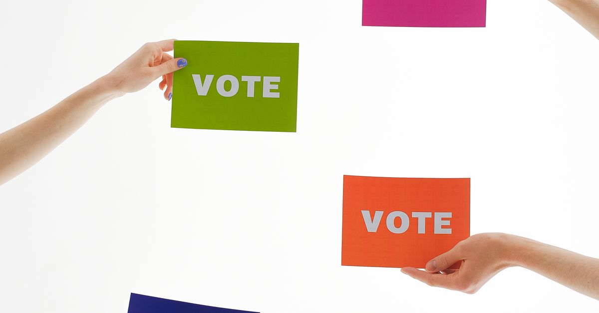 Photo by Anna Shvets Four hands holding colorful 'vote' cards, emphasizing democracy and participation.