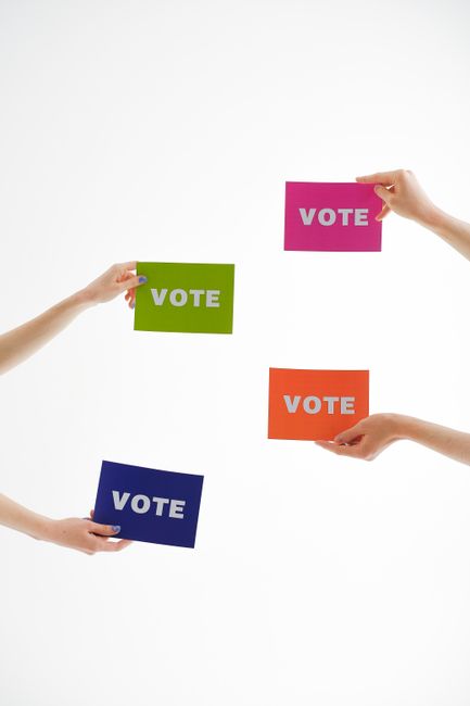 Photo by Anna Shvets Four hands holding colorful 'vote' cards, emphasizing democracy and participation.