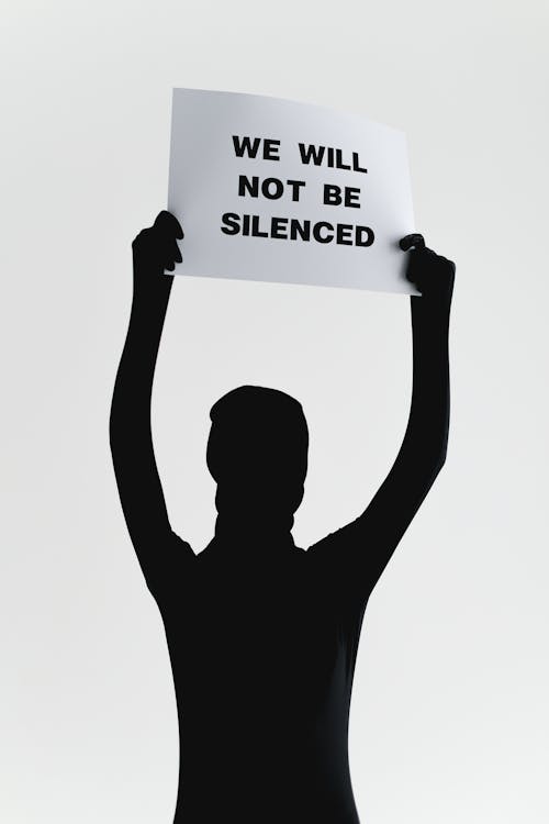 Person Wearing Black Zentai Suit Holding a Paper with Message 