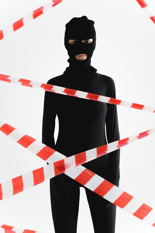 Free A Person in Black Zentai Suit Standing Behind Red and White Tape Stock Photo