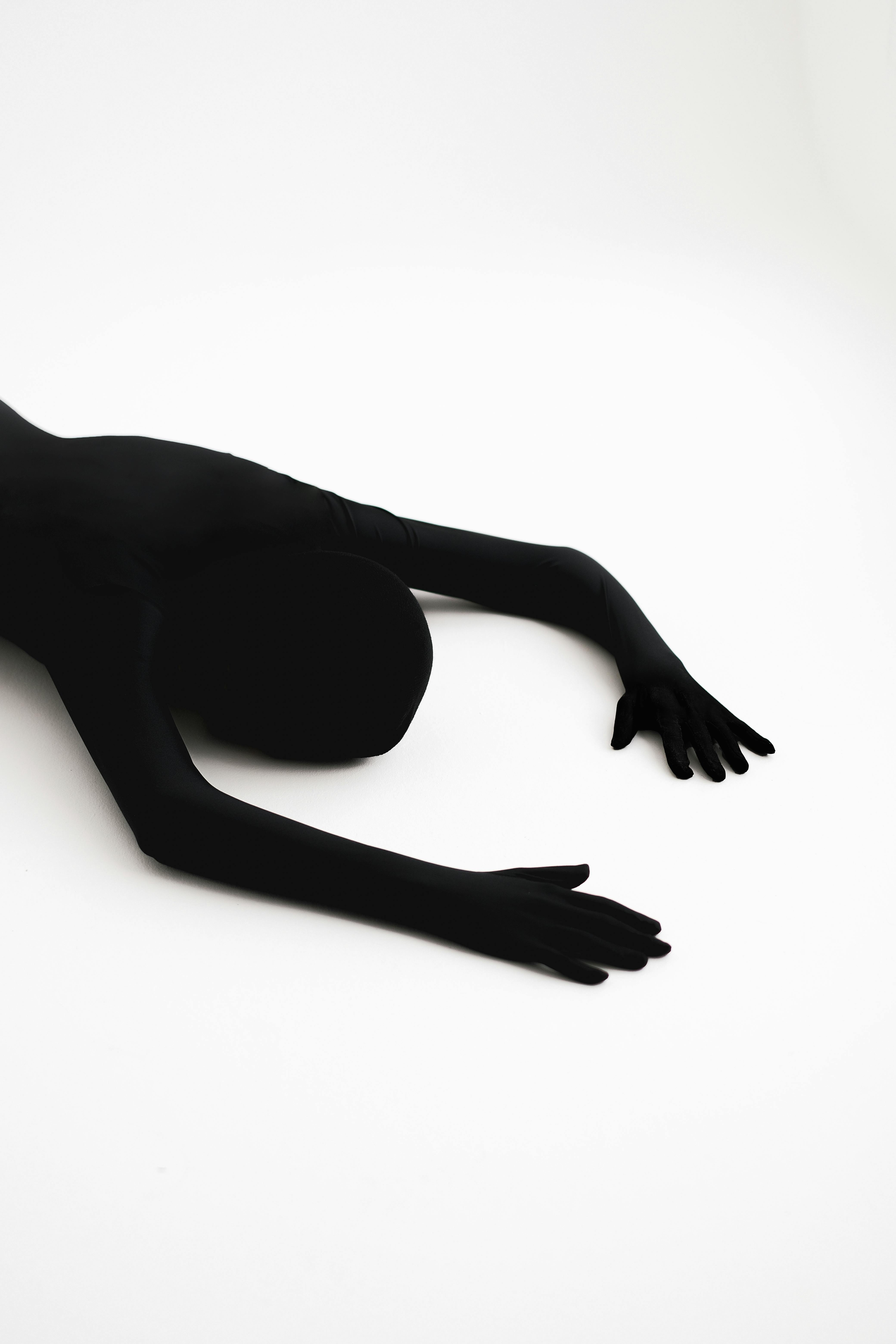 A Person in Black Zentai Suit Lying on a White Surface · Free
