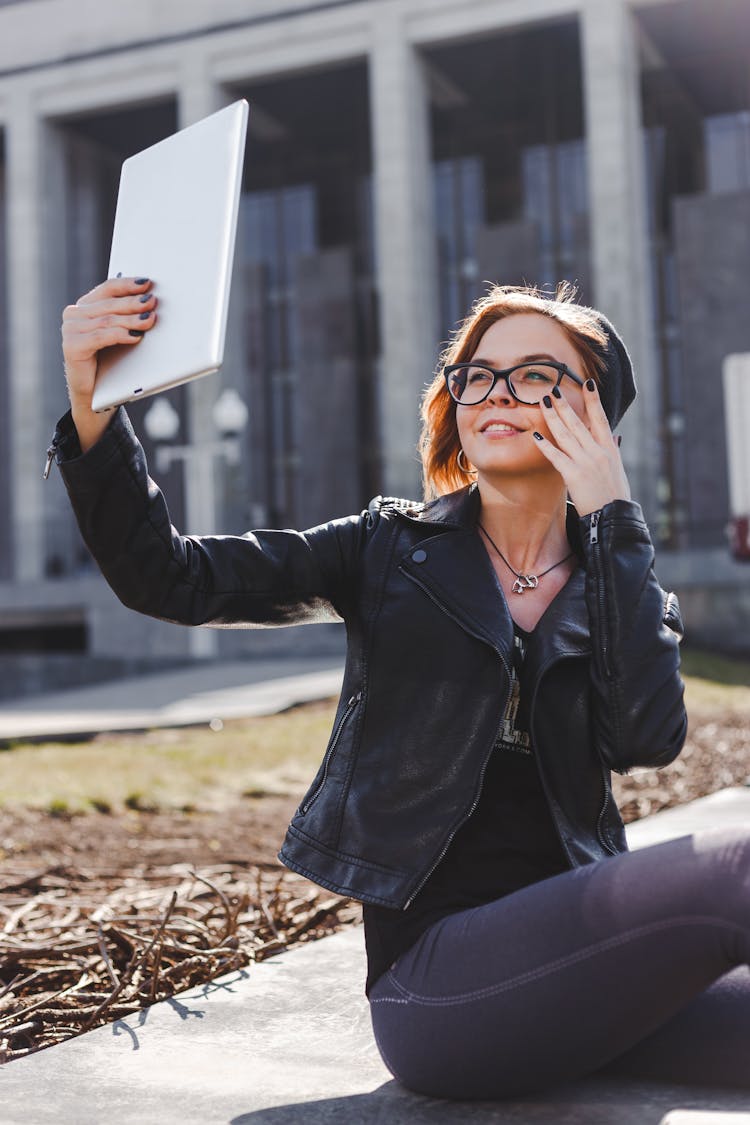 Woman In Black Leather Jacket Smiling While Holding An Ipad 