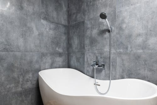 Free Bathroom interior with bathtub under shower on tile wall Stock Photo