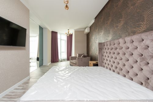 Free Interior of house with bed in front of TV on wall next to armchair and window with curtains near doorway Stock Photo
