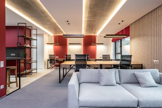 Spacious modern office featuring red accent walls, stylish furniture, and ample natural light.