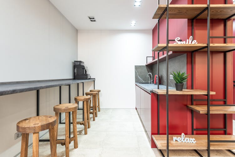 Office With Counter And Chairs Near Open Kitchen And Shelves